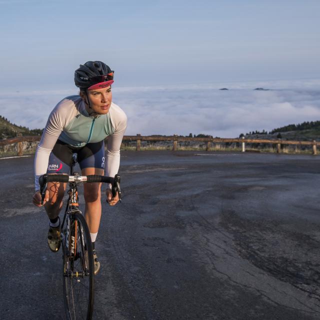 Cycliste en pleine ascension par un col de montagne sur le nuages