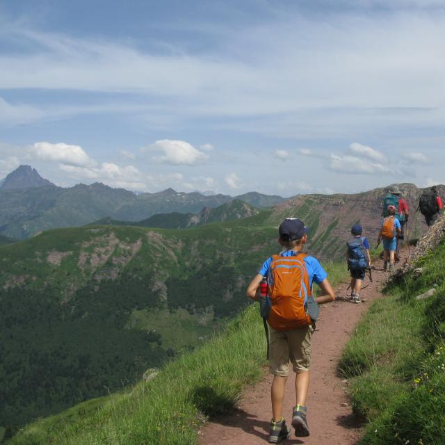 Sur le sentier du col de Saoubathou (vallée d’Aspe), on suit le guide géologue en marchant sur des roches rouges. Au fond, l’Ossau (Pyrénées béarnaises)