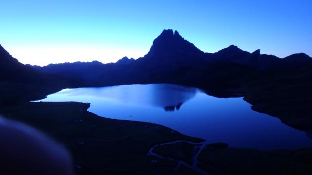 Lever de soleil pour les géorandonneurs sur la terrasse du refuge d’Ayous : en vedette, le pic du Midi d’’Ossau et son reflet dans le lac l (Pyrénées béarnaises)