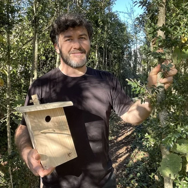 monsieur avec un nichoir dans la main pour les papillon et autres insectes en pleine forêt