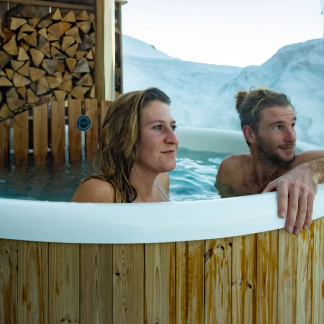 Détente et bien-être dans un bain nordique devant un paysage de montagnes enneigé des Pyrénées béarnaises.